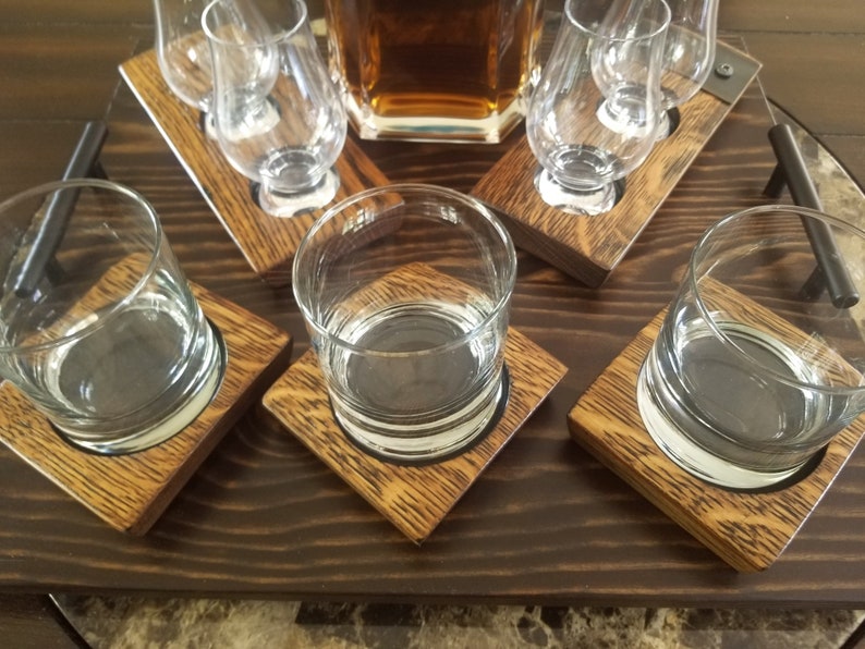 May include: A wooden serving tray with four clear glass tumblers and three clear glass shot glasses. The tray has a dark brown wood finish and is designed to hold drinks.