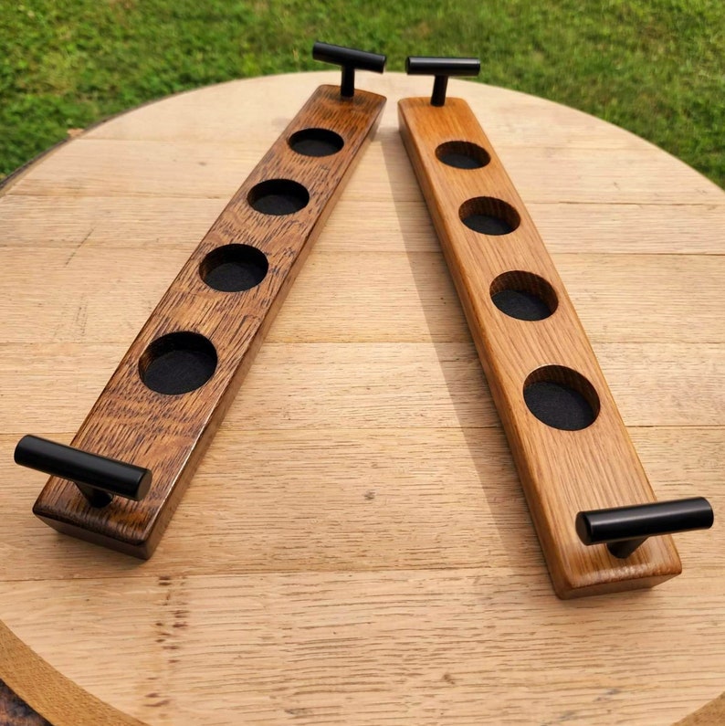 May include: Two wooden beer bottle holders with black metal handles. Each holder has five slots for bottles and a dark brown stain.