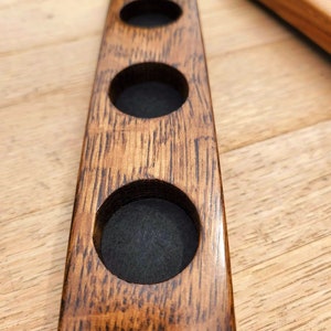 May include: A wooden coaster with four circular cutouts, ideal for holding glasses or mugs. The coaster is made from reclaimed wood and has a natural, rustic finish.