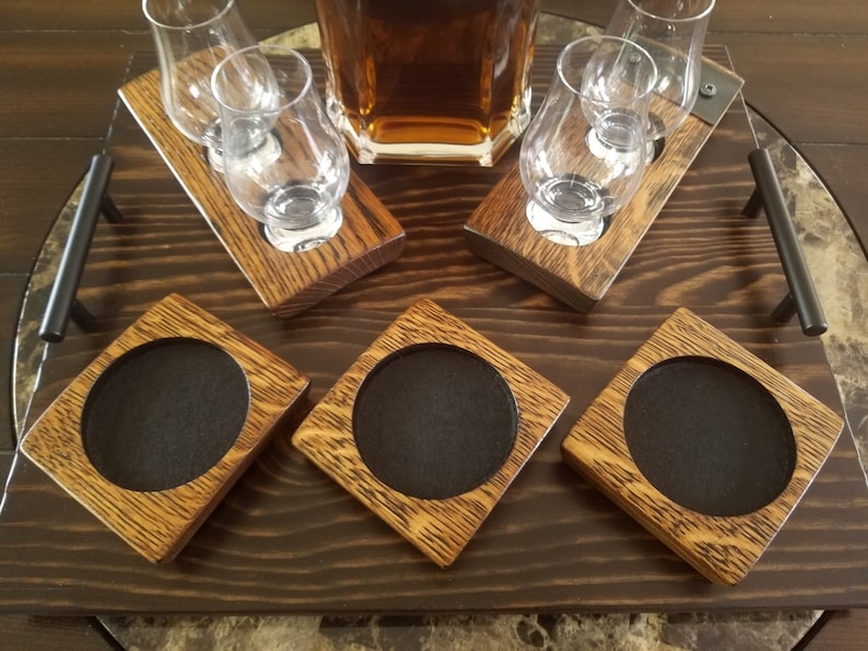 May include: A wooden serving tray with four round coasters and two sets of glass holders. The tray has a dark brown wood finish and the coasters and glass holders are made of light brown wood.