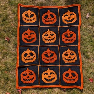 Può includere: Una coperta di Halloween fatta a mano con una griglia di facce di zucca arancioni su sfondo nero. La coperta ha un bordo arancione ed è esposta sull'erba. Un oggetto di arredamento per la casa accogliente e stagionale. Misura circa 120 cm x 150 cm.