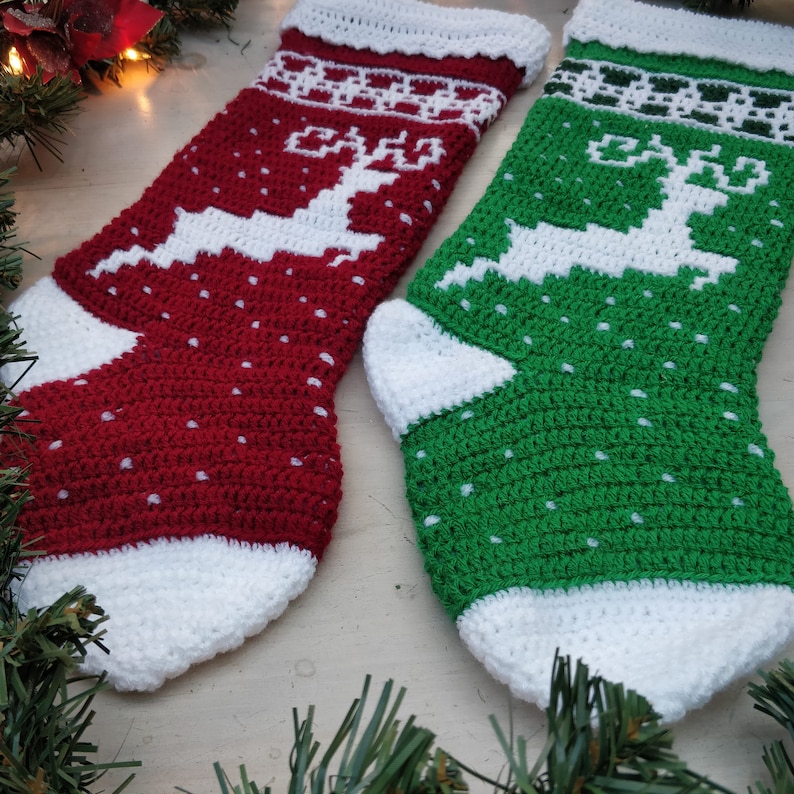 May include: Two crocheted Christmas stockings with white reindeer designs. One stocking is red with white polka dots and the other is green with white polka dots.