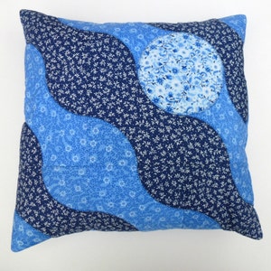 May include: A blue and white patterned pillow with a wavy design. The pillow is made of fabric and has a square shape.