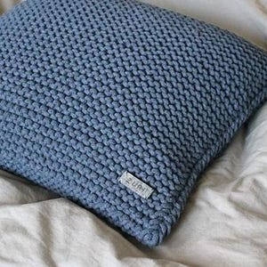 May include: A blue knitted throw pillow with a small white label that says "ZURI" on it.
