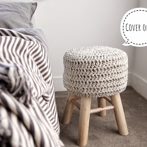 Könnte beinhalten: Ein gehäkelter Hockerbezug in Creme und Beige. Der Bezug ist mit einem strukturierten Stich gearbeitet und hat eine runde Form. Der Hockerbezug ist "COVER ONLY".