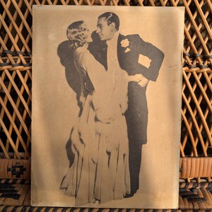 Peut inclure: Image vintage en noir et blanc d'un couple dansant. L'homme porte un smoking avec une fleur à la boutonnière, et la femme une robe fluide avec une étole de fourrure. Image sépia.