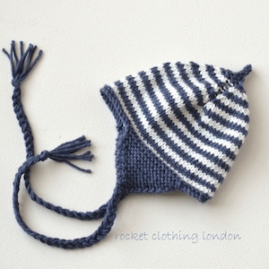 May include: A blue and white striped knitted hat with a long blue braided tie. The hat has a pointed top and a tassel on the tie.