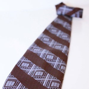 May include: A brown tie with a geometric pattern in shades of blue and white.