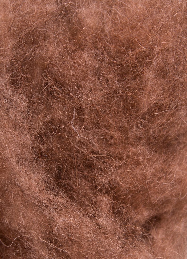 K&ouml;nnte beinhalten: Nahaufnahme eines braunen, flauschigen Materials. Die Textur ist weich und scheint aus Naturfasern zu bestehen.