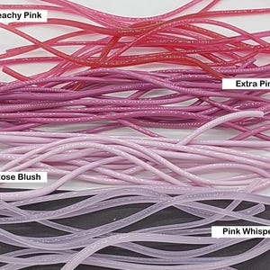 May include: A collection of flexible, thin, cylindrical cords arranged in four distinct color groups labeled Peachy Pink, Extra Pink, Rose Blush, and Pink Whisper. Each group features multiple strands of varying pink hues, ranging from deep coral to light lavender-pink, with a smooth, glossy finish.