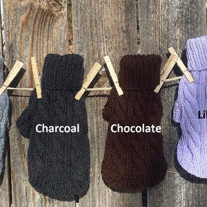 May include: Ten dog sweaters in various colours, including black, grey, charcoal, chocolate, lilac, and dark plum. The sweaters are hanging on a clothesline with clothes pegs.