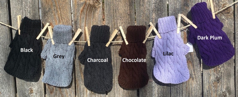 May include: Ten dog sweaters in various colours, including black, grey, charcoal, chocolate, lilac, and dark plum. The sweaters are hanging on a clothesline with clothes pegs.