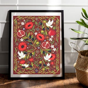 May include: A framed art print with a detailed floral design. It features red poppies, pomegranates, olives, and white doves on a burgundy background. The artwork is in a black frame and is displayed against a white wall. The artist's signature is in the upper right corner.