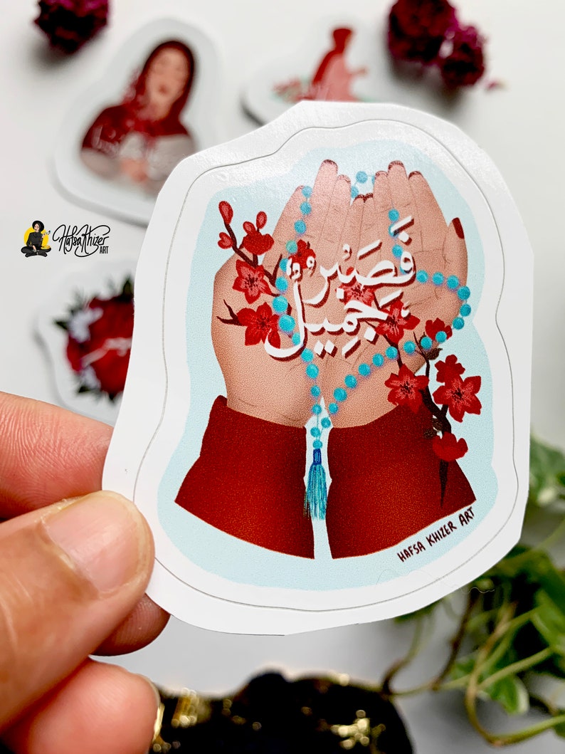 May include: A sticker with a blue and white prayer beads in two hands. The hands are surrounded by red flowers and the Arabic text "Wa Inna La Rabbi Na Shkur" is written in white. The sticker has the artist's name "Hafsa Khilzi Art" at the bottom.