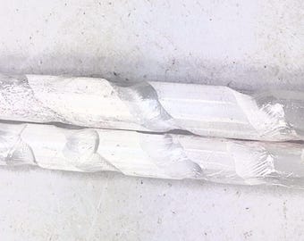 Puede incluir: Dos varillas blancas, retorcidas, con aspecto de cristal. Las varillas son translúcidas y tienen un ligero brillo iridiscente.