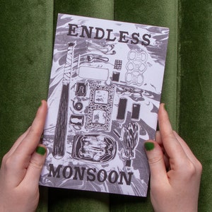 May include: A black and white illustration of a zine with the title "Endless Monsoon". The cover features a baseball bat, a pair of glasses, a can of soda, and other objects.
