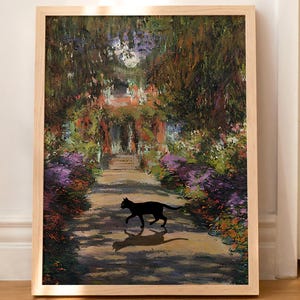 Op de afbeelding: Een ingelijste kunstdruk met een landschapsschilderij met een zwart katten silhouet. Het kunstwerk toont een tuinpad met kleurrijke bloemen en bladeren, omlijst door een natuurlijke houten lijst. De kat loopt over het pad.