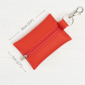 Puede incluir: Un monedero rectangular de color rojo con cierre de cremallera y un llavero de mosquet&oacute;n de metal plateado. El monedero mide 10 cm de largo y 7 cm de ancho, tal como indican las etiquetas de medici&oacute;n visibles en la imagen.