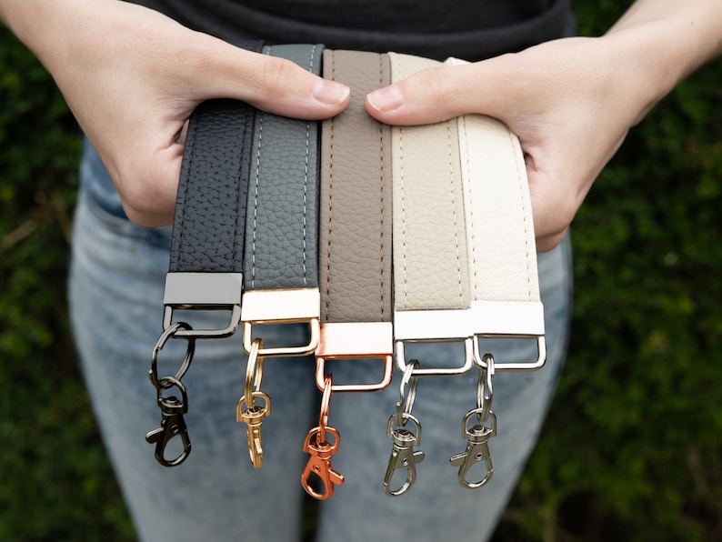 May include: Six leather straps with metal clasps and key rings in black, gray, brown, beige, and white.