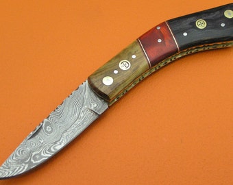 May include: A small pocket knife with a patterned steel blade and a wooden handle with brass accents. The handle is made of wood with red and black accents.