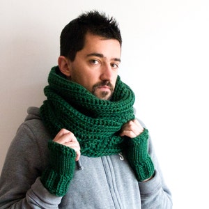 May include: A green knitted scarf and matching fingerless gloves. The scarf is folded and worn around the neck, while the gloves are worn on the hands.