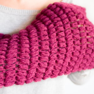 Peut inclure: Un gros plan d'une écharpe en crochet rose avec un motif texturé et ajouré.