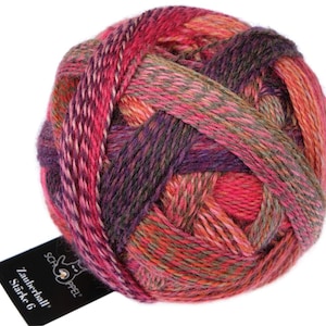 May include: A ball of multi-coloured yarn in shades of pink, purple, orange, and green. The yarn is tightly wound and has a textured appearance. A black tag with white text is attached to the yarn, with the words "Zauberball Stärke 6".