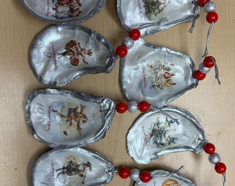 May include: A handmade oyster shell Christmas ornament garland. Each shell is painted silver and features a vintage illustration and a number from 1 to 12. The shells are strung together with red and silver beads.