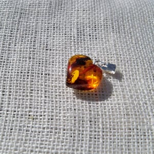 May include: A heart-shaped amber pendant with inclusions, set in silver with a bail for a chain.