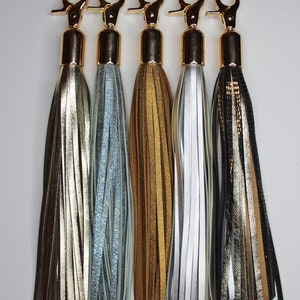 Pu&ograve; includere: Cinque portachiavi dorati con nappe in pelle di diversi colori: oro, argento, azzurro, marrone e nero.