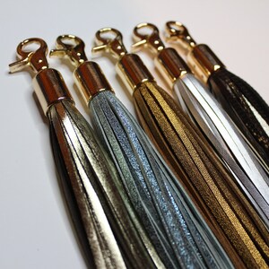 Pu&ograve; includere: Cinque nappine in pelle con chiusure in metallo dorato. Le nappine sono in tonalit&agrave; oro, argento, marrone, bianco e nero.