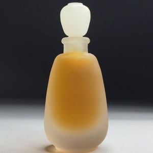 May include: A small, frosted glass bottle with a clear, round stopper. The bottle is filled with a golden liquid.
