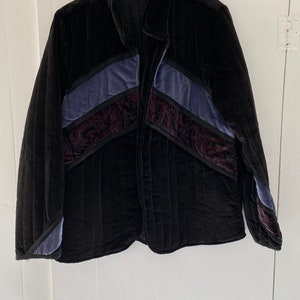 May include: A black quilted jacket with a paisley pattern and blue and burgundy accents. The jacket has a zip closure and a collar.
