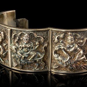 May include: Silver bracelet with intricate embossed designs of figures riding animals. The bracelet is made of silver and has a polished finish.