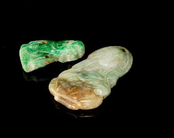 May include: Two jade pendants, one green with intricate carvings and the other a light green and brown figure pendant.