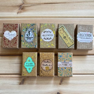 May include: Ten small, square, cardboard boxes with glitter and gold accents. Each box has a different label with text and a graphic. The labels include: Amortentia, Mermaid Tears, Gillyweed, Polyjuice Potion, Unicorn Horn Dust, Floo Powder, Felix Felicis, Veritaserum.