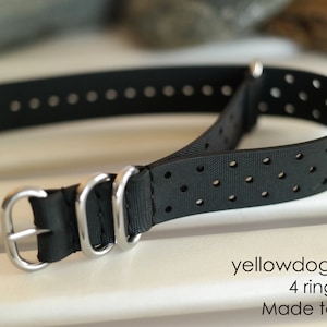 Könnte beinhalten: Schwarzes, perforiertes Uhrenarmband mit silberner Hardware. Das Armband ist ein 4-Ring-NATO-Stil und wird nach Maß gefertigt. Der Text "yellowdogwatchstraps 4 ring NATO Made to Measure" ist unterhalb des Armbands sichtbar.