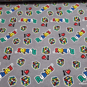 May include: Gray fabric with a repeating pattern of colorful Rubik's Cubes and the text "I ♥ Rubik's".