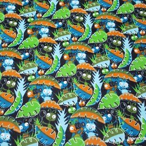 May include: A black fabric with a repeating pattern of blue, green, and orange cartoon ants carrying magnifying glasses. The ants are surrounded by green and orange leaves.