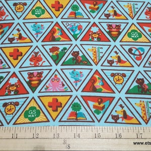 Puede incluir: Una tela azul con un patr&oacute;n repetitivo de parches triangulares coloridos. Cada parche presenta un dise&ntilde;o diferente de insignia de Girl Scout, incluyendo una cruz roja, un libro, un reloj, un gato, una jirafa y un pulpo. El texto "GS WAY" aparece en algunos de los parches.