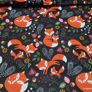 May include: Black fabric with a repeating pattern of orange foxes with white accents. The foxes are surrounded by green leaves, brown acorns, and small white flowers.