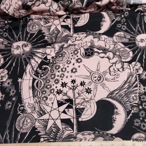 May include: Black and white celestial print fabric with a pink background. The print features stars, moons, suns, and other celestial symbols.
