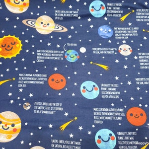 May include: A blue fabric with white stars and yellow shooting stars. The fabric features illustrations of planets with smiling faces and text about the planets. The text includes facts about the planets, such as their size, distance from the sun, and interesting features. The fabric is perfect for a child's room or a space-themed project.