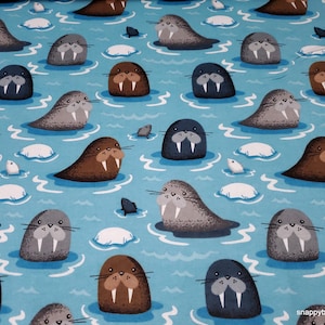 May include: A blue fabric with a repeating pattern of brown, gray, and black walruses on a light blue background. The walruses are all facing forward with their tusks showing. The fabric is perfect for quilting, sewing, and crafting.