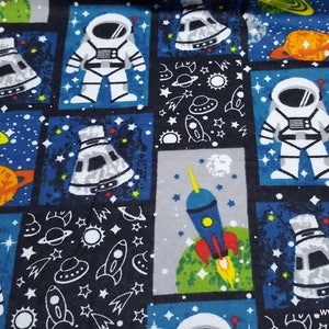 May include: A blue and black fabric with a repeating pattern of astronauts, spaceships, planets, stars, and rockets. The fabric is perfect for quilting, crafts, and other projects.