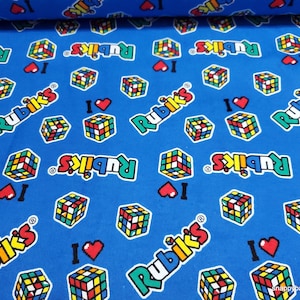 May include: Blue fabric with a repeating pattern of colorful Rubik's Cubes and the text "Rubik's" with a heart symbol.