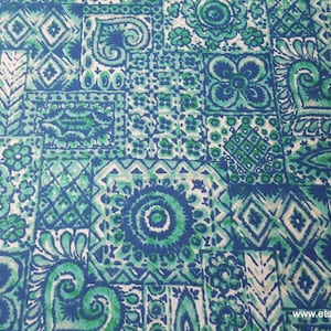 May include: A white fabric with a blue and green geometric pattern. The pattern is made up of squares, circles, and other shapes. The fabric is perfect for quilting, sewing, or crafting.