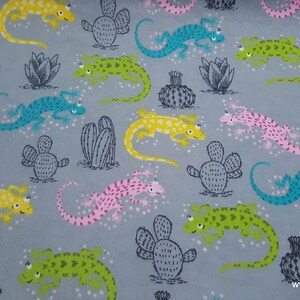 May include: A gray fabric with a repeating pattern of colorful lizards and cacti. The lizards are green, yellow, blue, and pink. The cacti are gray and green.