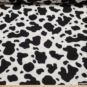 May include: Black and white cow print fabric. The fabric has a repeating pattern of black spots on a white background.