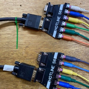 May include: Two black HOTLINE S6 video capture cards with multiple cables connected. The cables are red, orange, yellow, green, blue, and grey. The cards have a 15-pin VGA connector and a 9-pin connector.